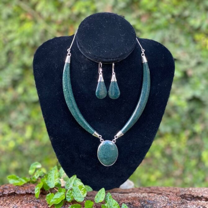 A jade and silver earring set photographed in front of a natural green background