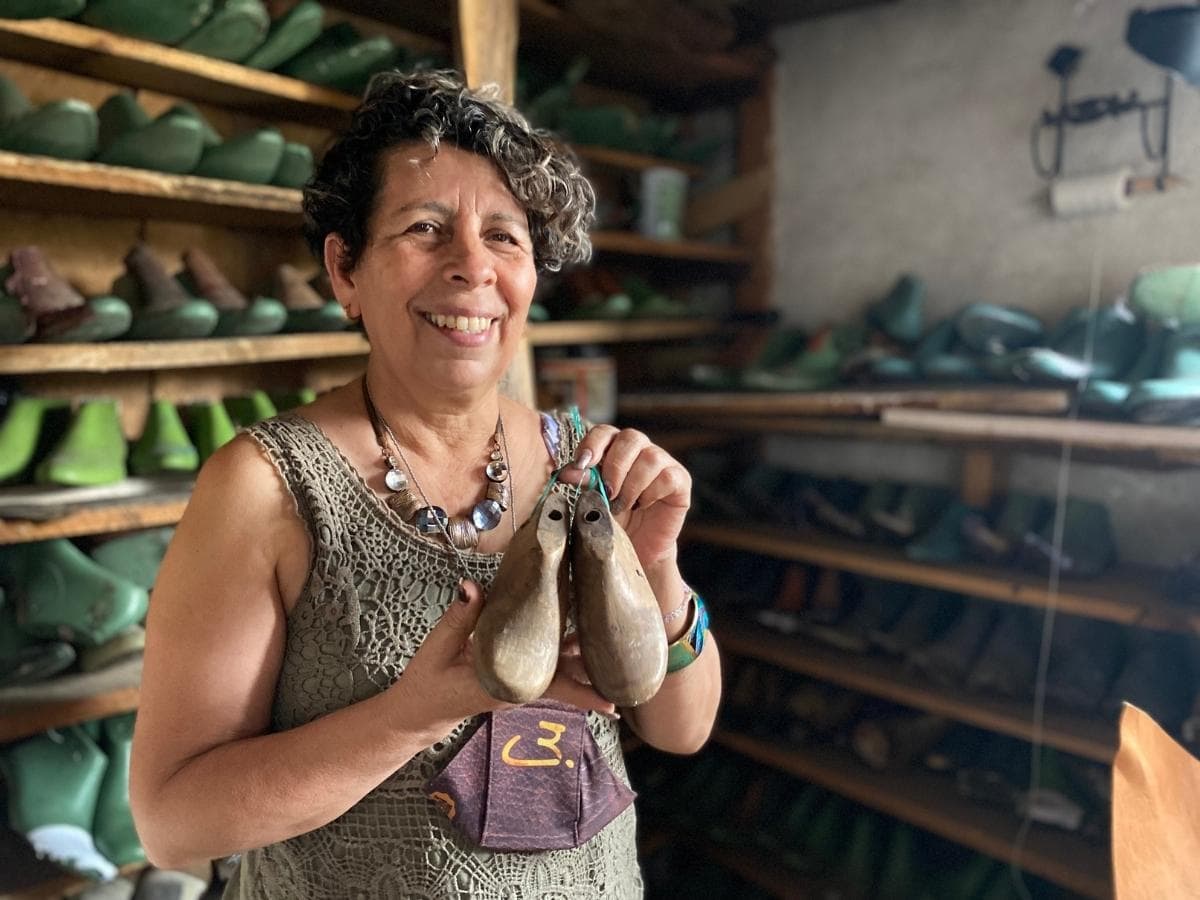 A woman who is a leather worker holding a mold to help her make shoes