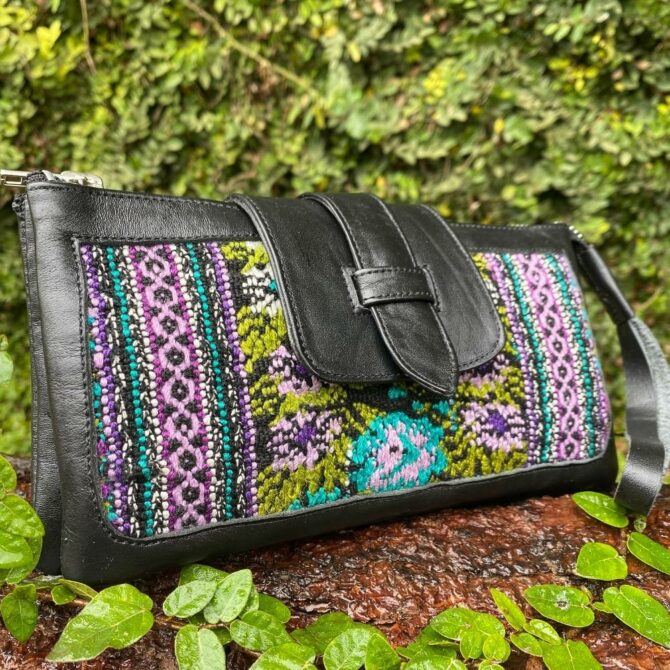 Black leather clutch with purple, blue, and green traditional Guatemalan Fabric sown into it. Closes with a latch and has a wristband