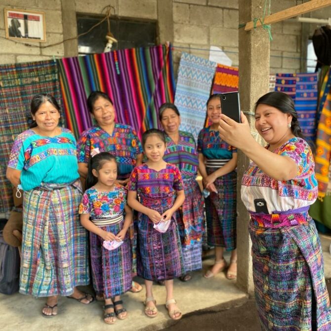 A ground of women all dressed in traditional Mayan clothes gather together for a selfie